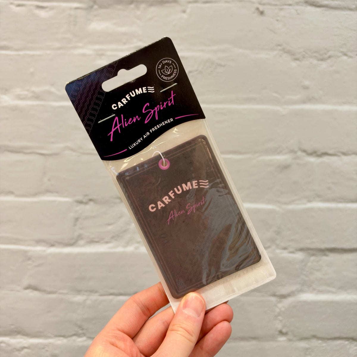 Carfume Alien Spirit hanging car air freshener in black packaging with pink lettering.