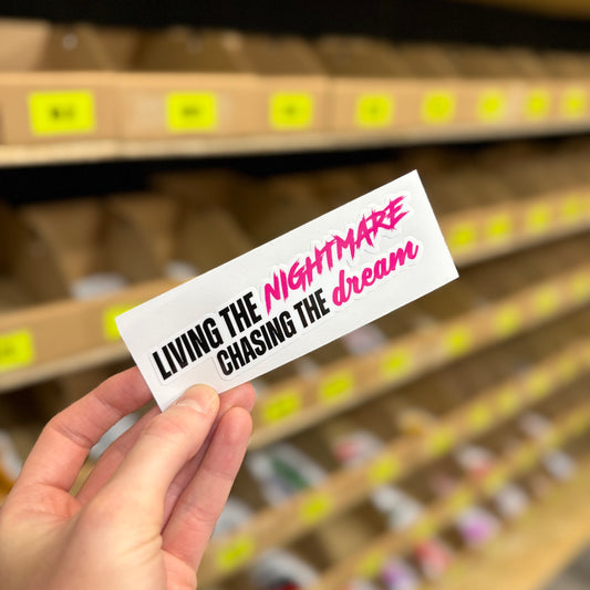 Typography design reading “Living the nightmare chasing the dream” funny vinyl sticker.