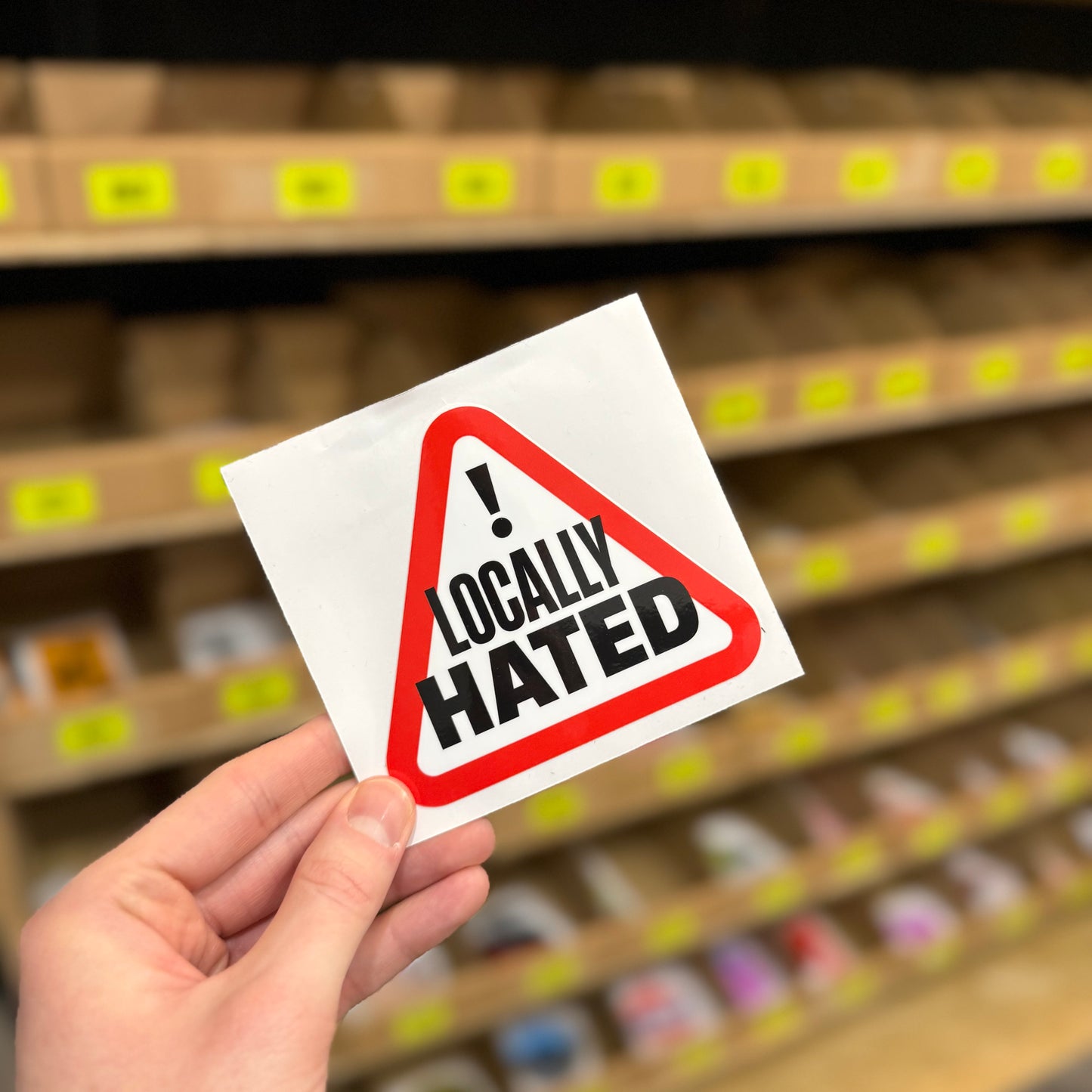 Funny warning style sticker reading “locally hated” inside red triangle sign