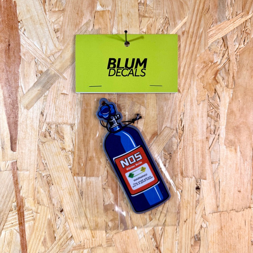 Blue NOS bottle-shaped car decal with a green 'BLUM DECALS' sign on a wooden surface