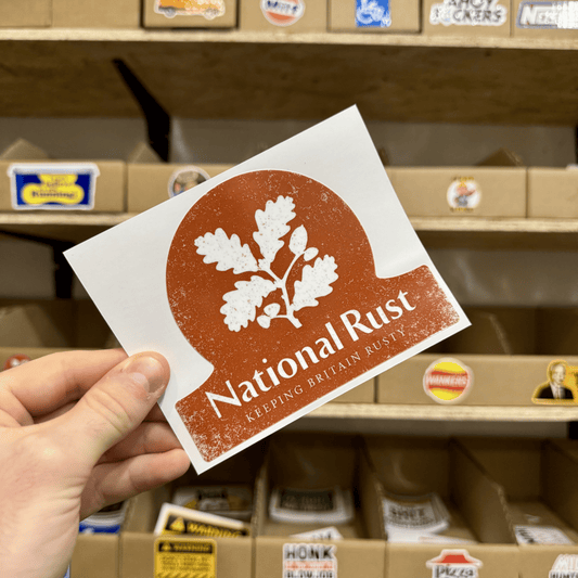 Vintage-style National Rust sticker in red and white featuring an oak leaf silhouette and the slogan ‘Keeping Britain Rusty.’