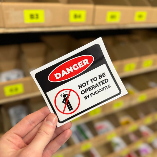 Funny danger sign sticker reading “not to be operated by fuckwits” parody warning design