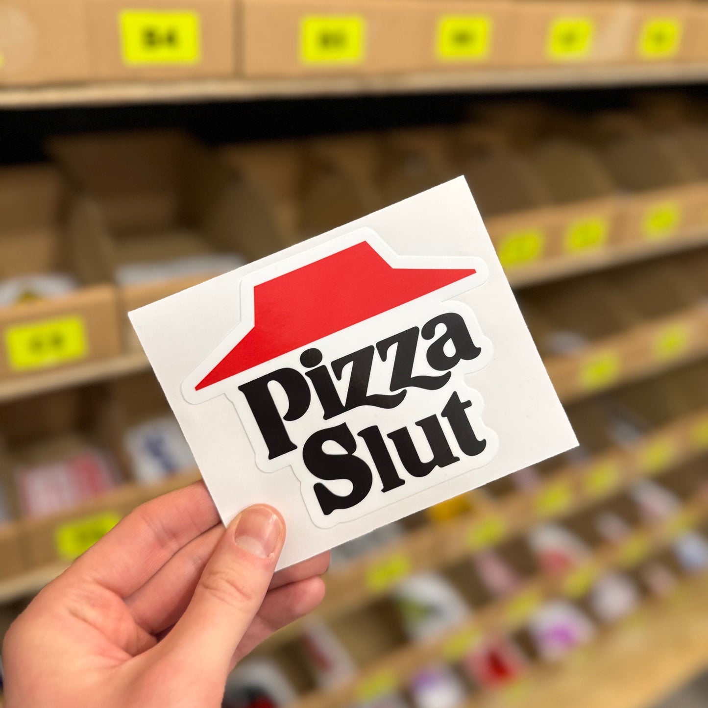 Funny food slogan sticker reading “pizza slut” in bold black lettering