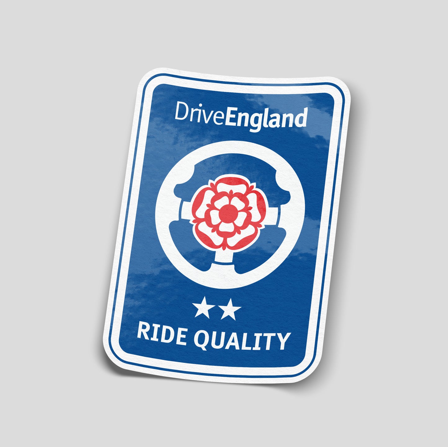 Drive England Ride Quality funny vinyl car sticker styled like a parody road sign with steering wheel and red rose emblem. Gloss laminated waterproof UK made decal for cars, vans and British car culture fans.