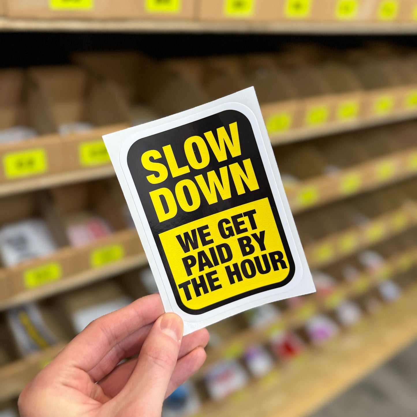Slow down we get paid by the hour funny vinyl sticker in black and yellow sign-style design