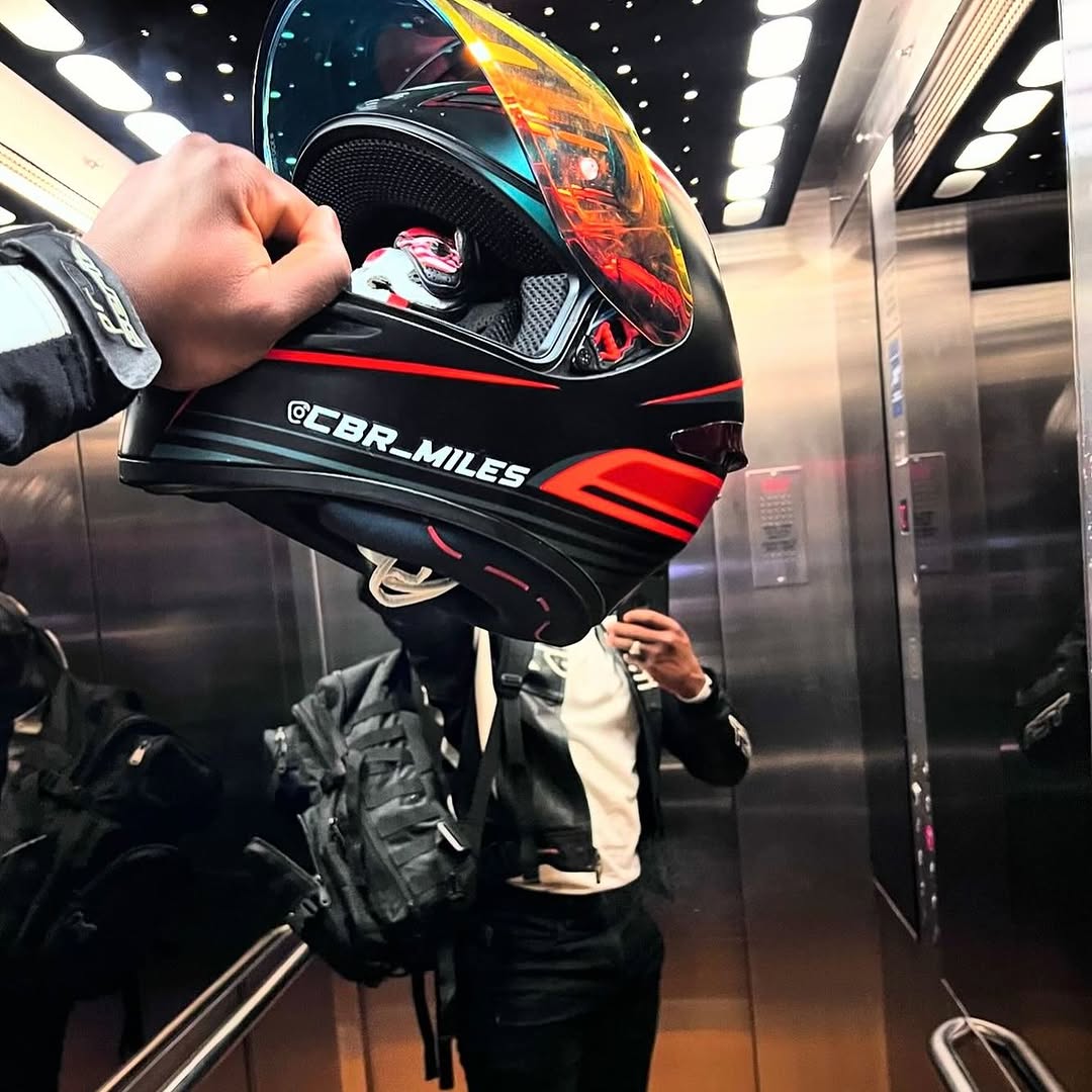Close-up of a black and white Instagram handle sticker on a motorcycle helmet being held up, showcasing custom social media branding for riders.