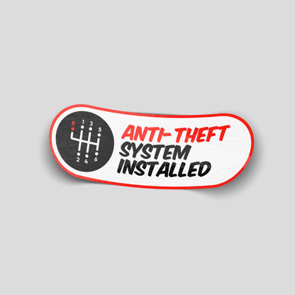 Funny “Anti-Theft System Installed” vinyl car sticker with manual gear icon, novelty decal perfect for cars, vans and garages.