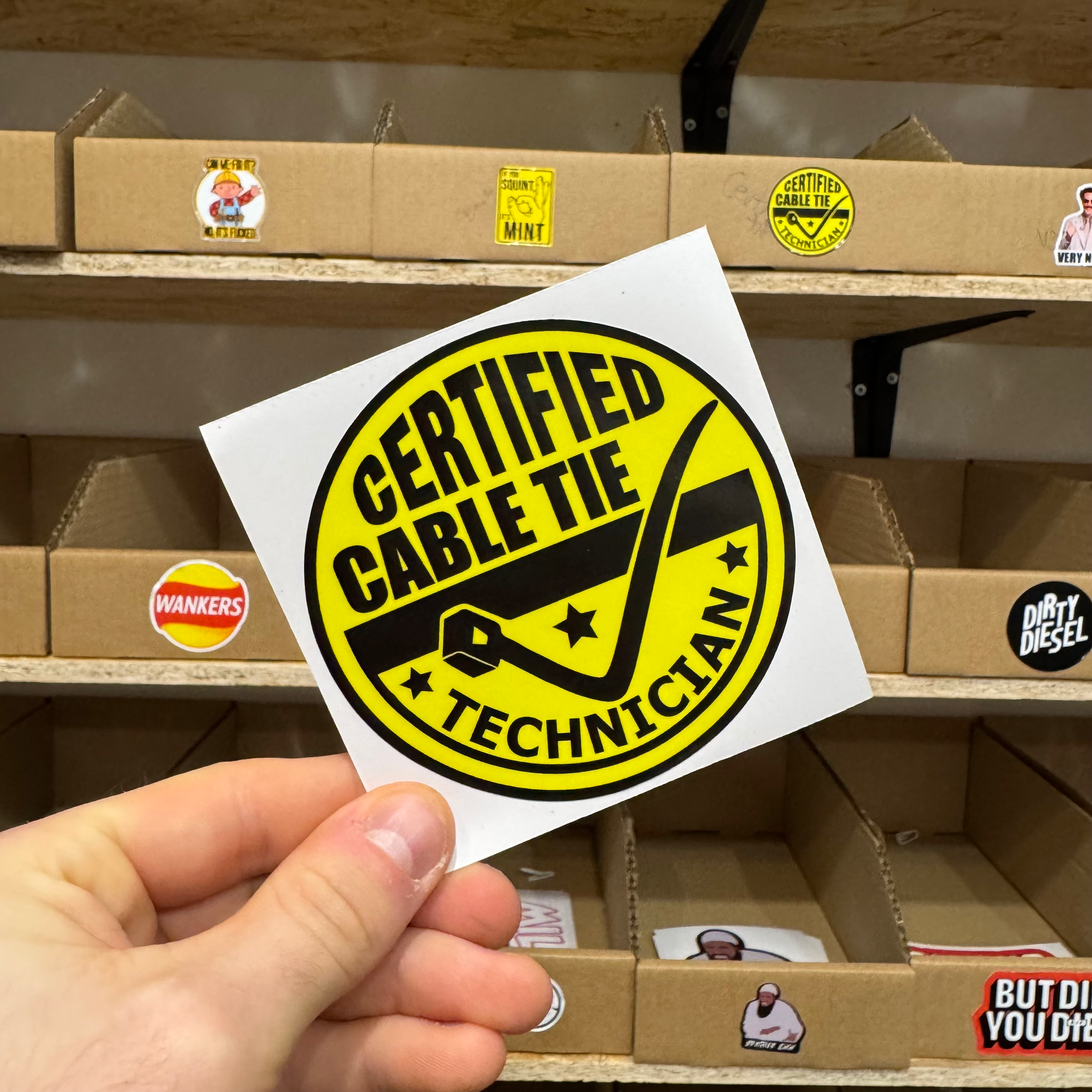 Yellow circular sticker with bold black text reading ‘Certified Cable Tie Technician’ and a cable-tie graphic.