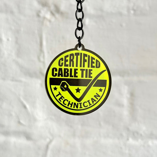 Funny “Certified Cable Tie Technician” acrylic keychain with bright yellow badge design, glossy finish and black chain, perfect gift for mechanics and DIY enthusiasts.