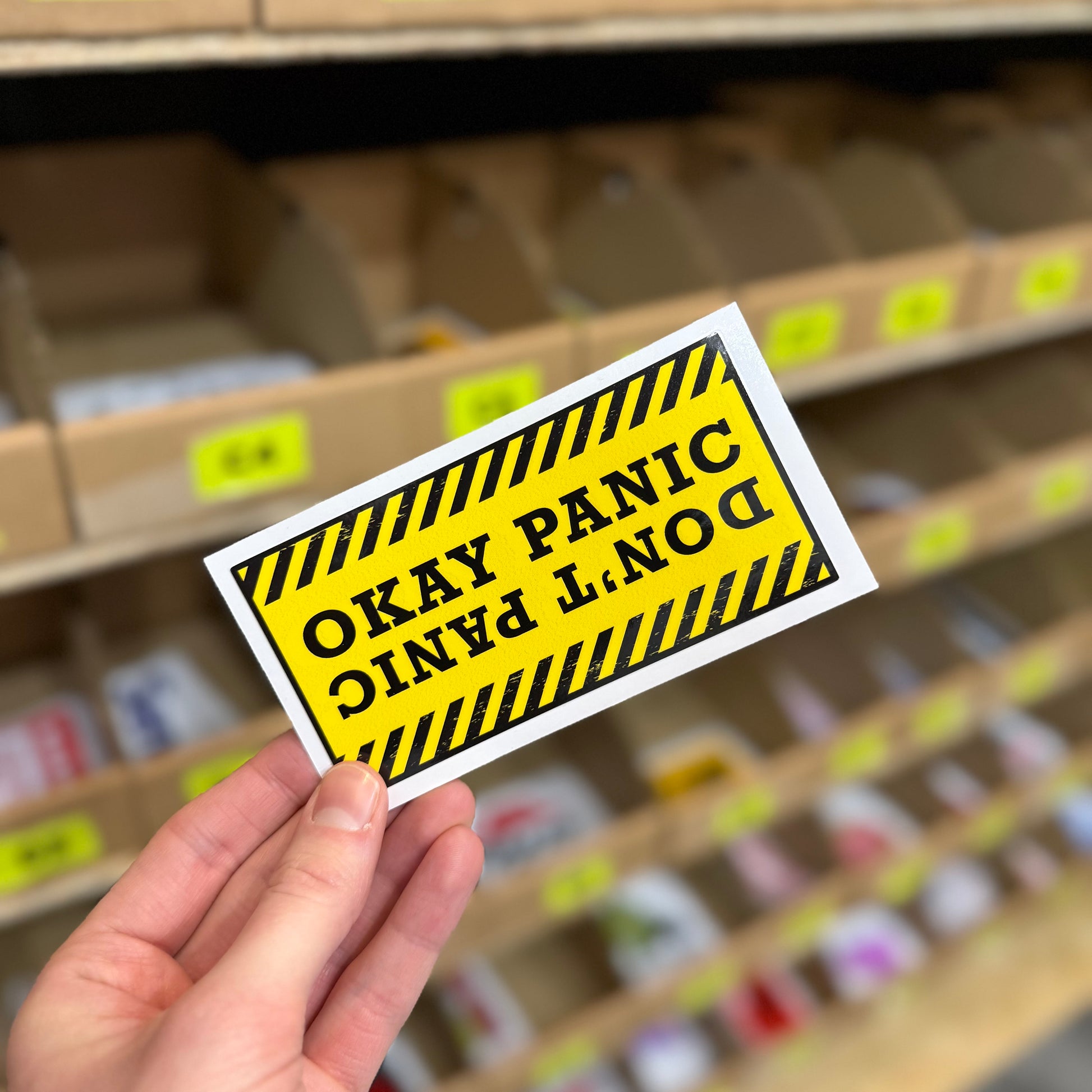 Funny warning style sticker reading “don’t panic okay panic” yellow hazard design