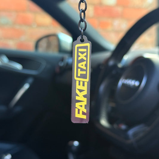 Funny “Fake Taxi” keychain with bold yellow and black design, novelty automotive keyring for car enthusiasts, durable acrylic accessory UK