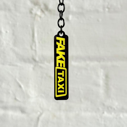 Funny “Fake Taxi” acrylic keychain with bold black and yellow design, glossy finish and black chain, novelty car keyring for automotive humour fans.