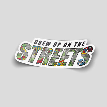 “Grew Up on the Streets” funny car sticker with text filled by a children’s play‑mat road pattern, UK nostalgia humour decal.