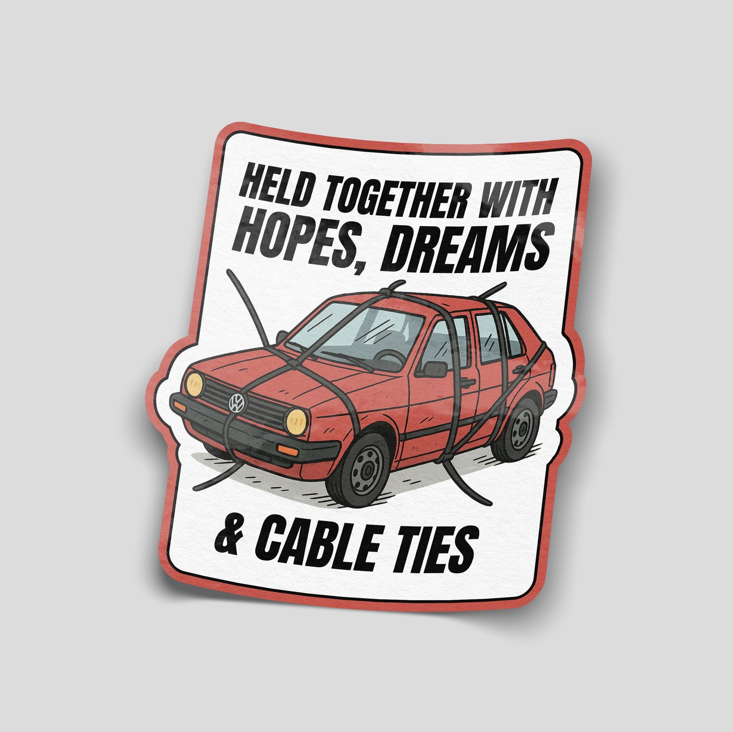 Illustrated funny car sticker showing an old red car strapped together with cable ties, captioned “Held together with hopes, dreams & cable ties”, UK motoring humour decal.
