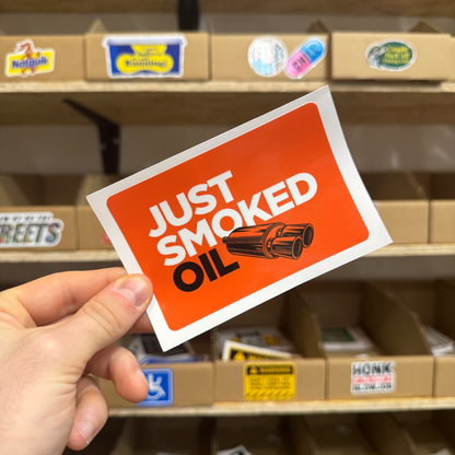 Bold orange automotive-themed sticker featuring exhaust pipes and the text ‘Just Smoked Oil.'