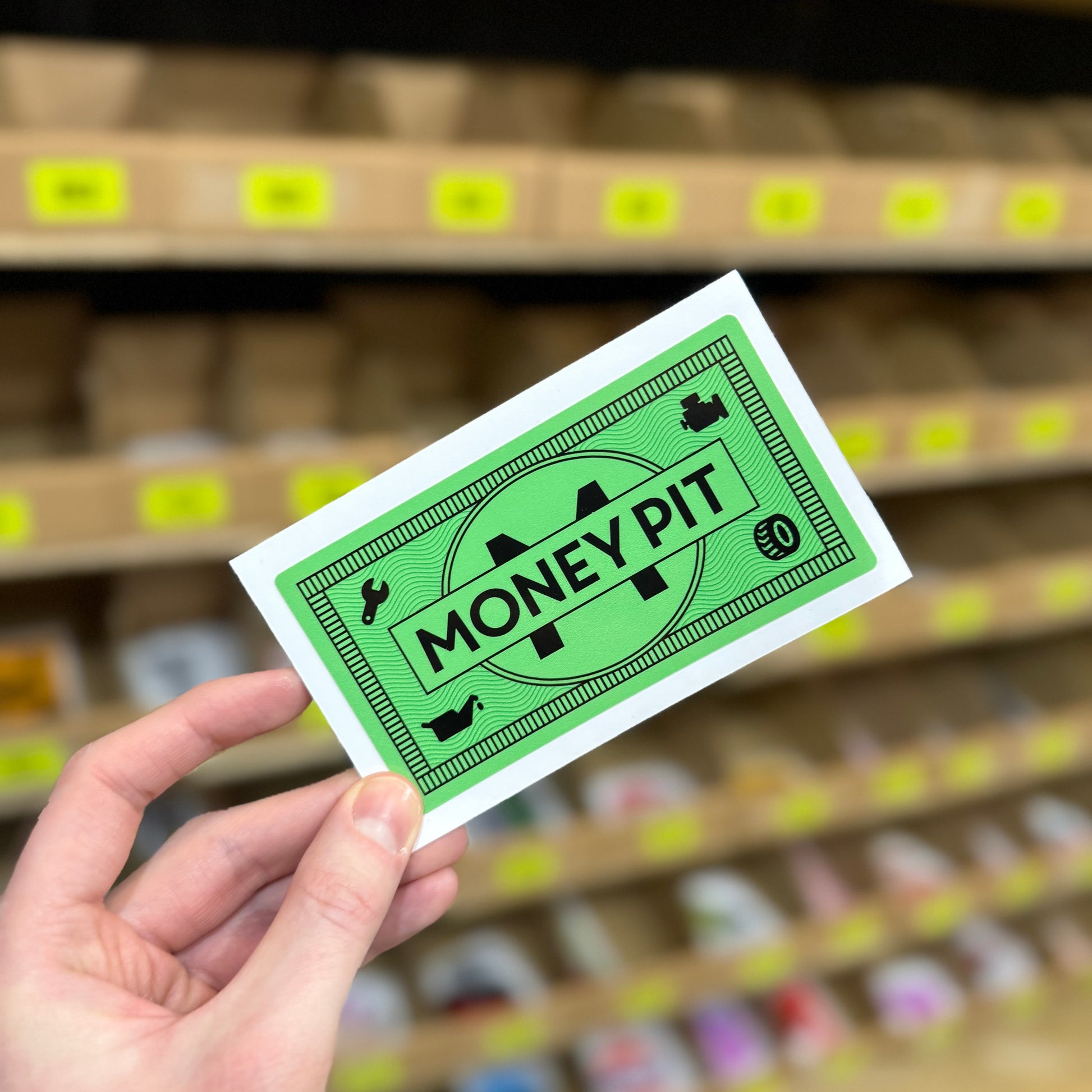 Funny car sticker designed like green banknote reading “money pit” parody graphic