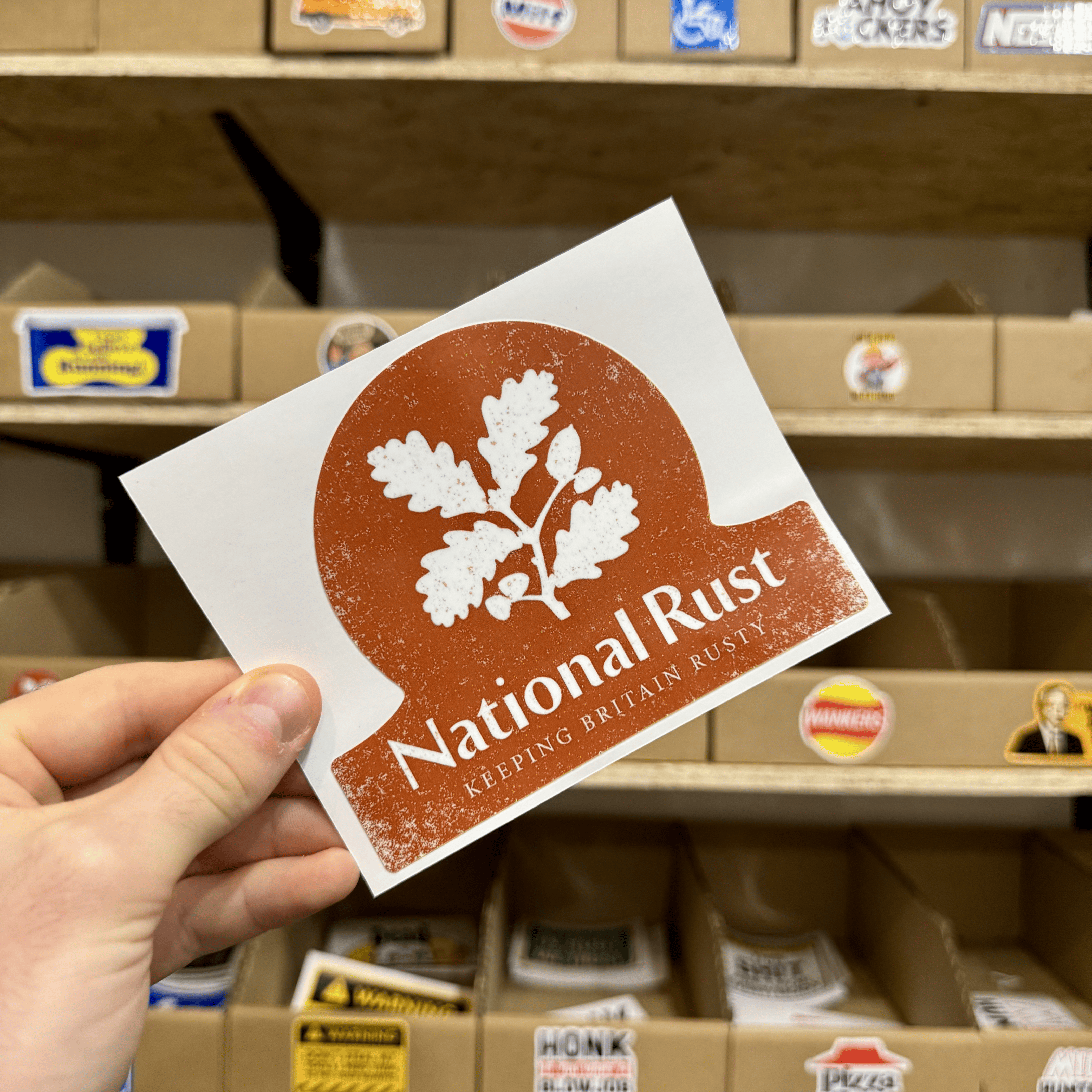 Vintage-style National Rust sticker in red and white featuring an oak leaf silhouette and the slogan ‘Keeping Britain Rusty.’
