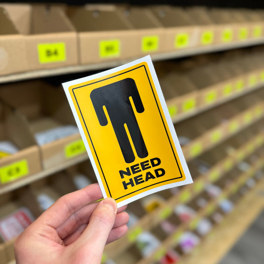 Funny warning style sticker reading “need head” in yellow road sign design