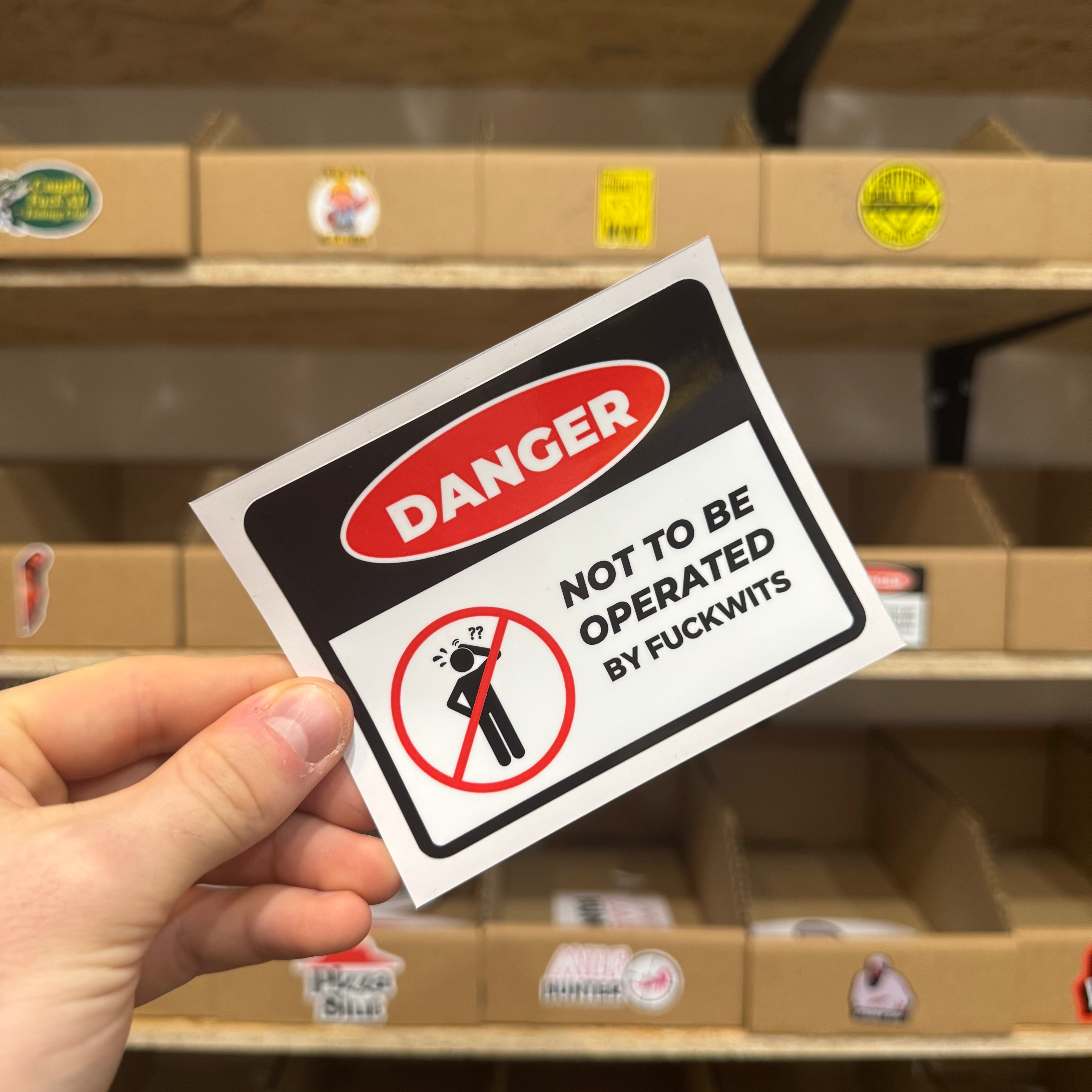 Warning-style sticker reading ‘Danger: Not to be operated by fuckwits’ with a crossed-out stick figure illustration.