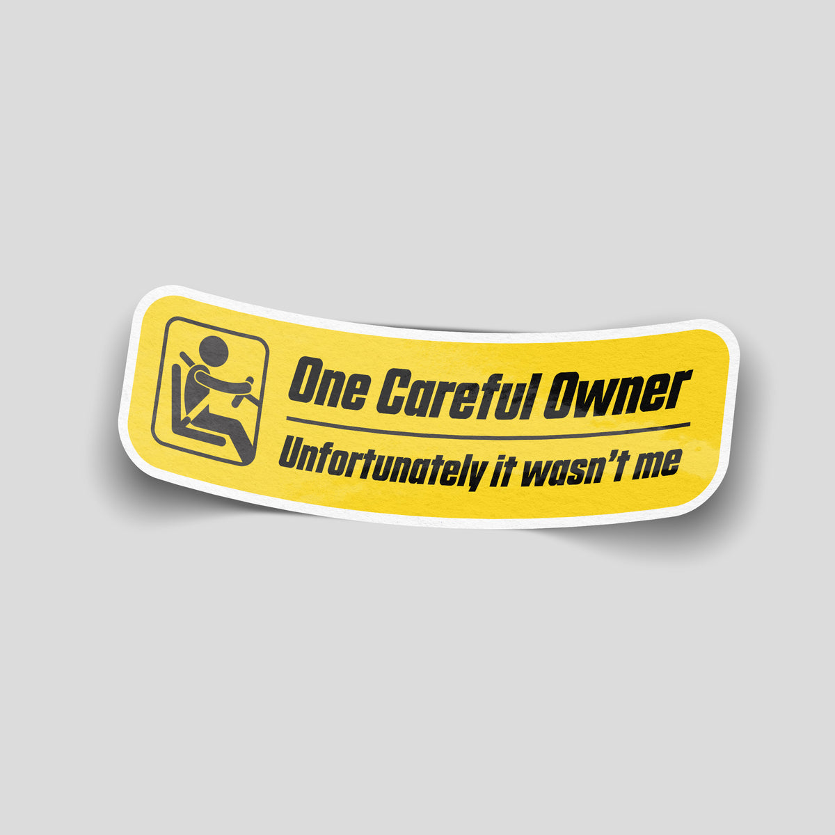Yellow car sticker with a black driver symbol and the wording “One Careful Owner — Unfortunately it wasn’t me”.