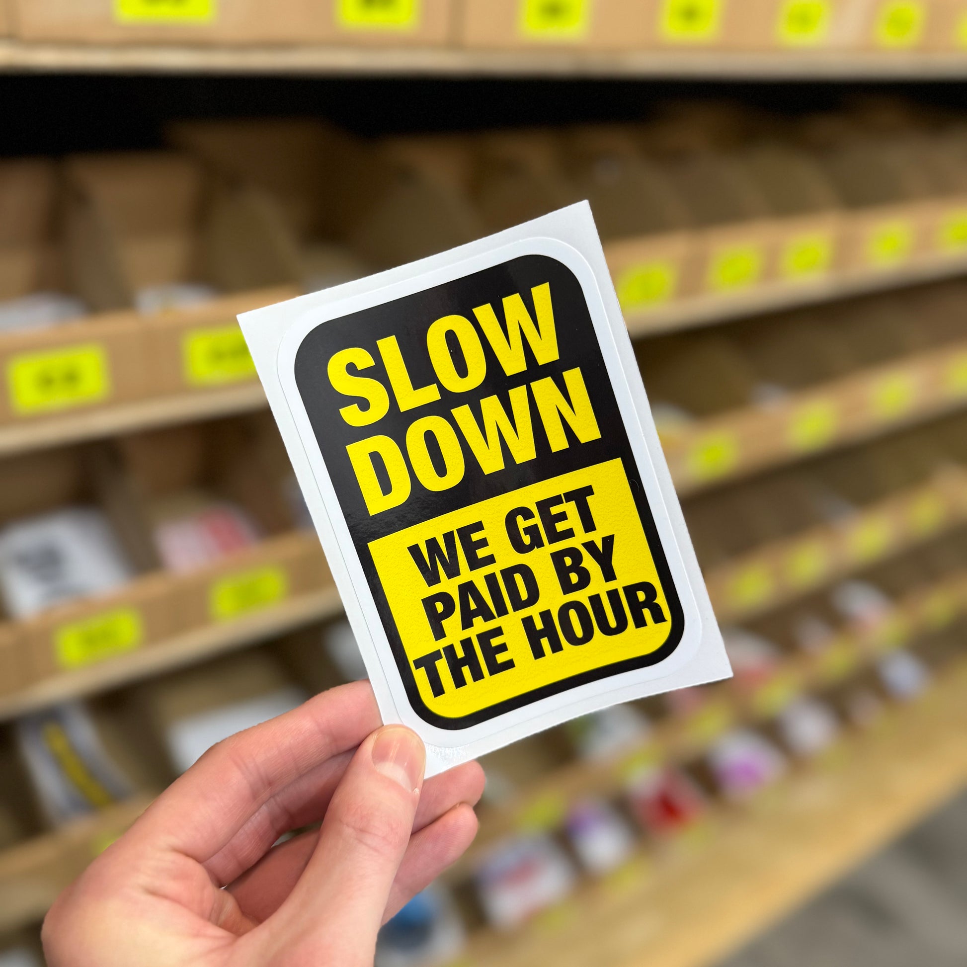 Slow down we get paid by the hour funny vinyl sticker in black and yellow sign-style design