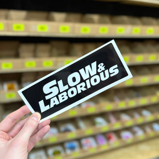 Slow and laborious funny vinyl sticker with bold white text on black background
