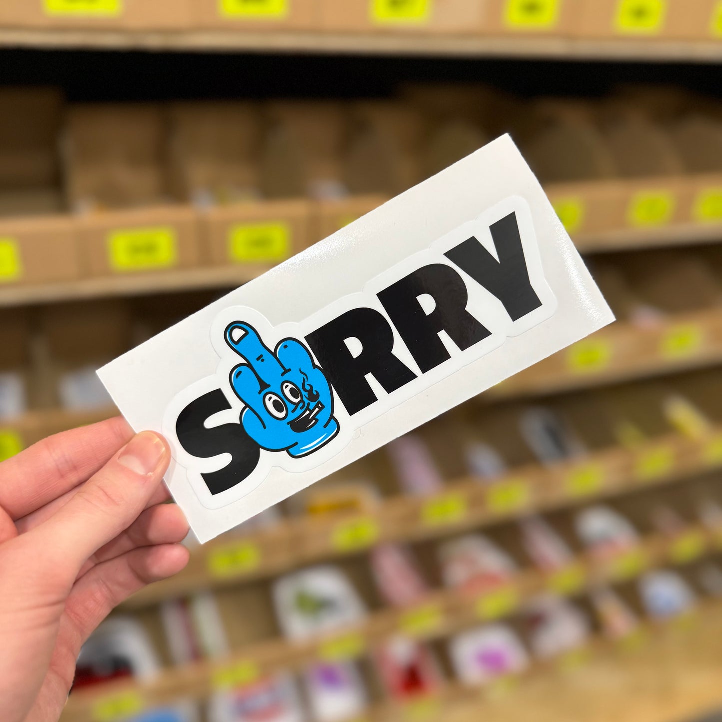 Sorry funny vinyl sticker with blue cartoon hand making rude gesture