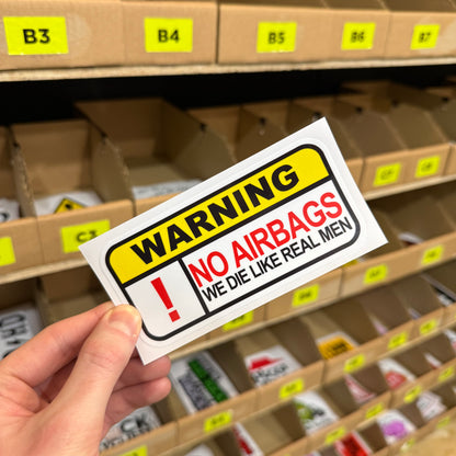 Warning sign reading “No airbags, we die like real men” funny vinyl sticker.